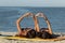 Two beautiful girls in swimsuits lay on the yellow surfboard on the sandy beach near the sea and show with fingers