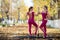 Two beautiful gymnasts do pair tricks on a portable platform in a beautiful autumn park. Two friends in the same body dance on a