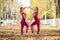 Two beautiful gymnasts do pair tricks on a portable platform in a beautiful autumn park. Two friends in the same body dance on a