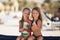 Two beautiful happy girl on the beach near the sea with shells in their hands