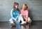 Two beautiful happy young women real friends in casual dress sit near concrete wall