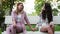 Two beautiful lesbian women feel shy, sitting on a bench and join hands