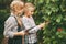 Two beautiful little girls are exploring nature by writing their research on a tablet. Curious children.