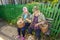 Two beautiful mature women sit on a bench near the house with baskets of mushrooms