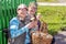 Two beautiful mature women sit on a bench near the house with baskets of mushrooms