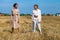 Two beautiful models in a beige suit posing on a background of wheat in a cut field