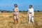 Two beautiful models in a beige suit posing on a background of wheat in a cut field