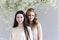 Two beautiful multicultural young women over grey background