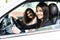 Two beautiful and pretty girls driving in car of their dream. Happy female driver holding hands on steering wheel. Girls smiling