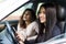 Two beautiful and pretty girls driving in car of their dream. Happy female driver holding hands on steering wheel. Girls smiling