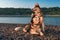 Two beautiful Siberian husky rest side by side on the shore. Formal portrait on the background of summer beach.