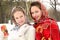 Two beautiful smiling girls in painted shawls stand on the background of a winter forest during a winter holiday. Russian