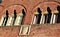 Two beautiful twin mullioned windows and an heraldic coat of arms in the red brick wall of a historic building in Lucca.