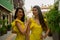 Two beautiful twin sisters violinists in yellow concert dresses are posing with electric violins on narrow Ottoman street of old