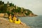 Two beautiful twin sisters violinists in yellow concert dresses are sitting on rocks by the Mediterranean sea with electric