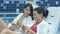 Two beautiful women checking their phones sitting on poolside chaise longues