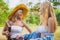 Two beautiful women in conversation while walking with bicycle at park