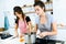 Two beautiful women cutting and cooking fresh vegetables in kitchen.