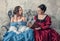 Two beautiful women in medieval dresses on the sofa reading book