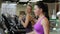 Two beautiful women run on a treadmill in a fitness club.