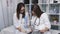 Two beautiful young doctors women double check files with paper documents. Two women doctor in the examining room filing