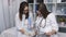 Two beautiful young doctors women double check files with paper documents. Two women doctor in the examining room filing