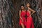 Two beautiful young fashionable models in red dresses outdoors at sunset