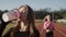 Two beautiful young fitness women working out outdoors. Fitness girls at the stadium. In the foreground, the girl drinks