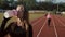 Two beautiful young fitness women working out outdoors. Fitness girls at the stadium. In the foreground, the girl drinks