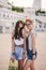 Two beautiful young girls on a skateboard in the city.