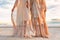 Two beautiful young woman in elegant boho dresses oudoors at sunset