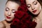 Two beautiful young women with amazing make-up in roses. Cosmetic care, makeup. Sensuality twins. Stylish attractive woman in flo