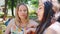 Two beautiful young women blonde and brunette emotional talking in summer Park.