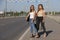 Two beautiful young women are hitchhiking on the road and try to find someone to take them to their hotel