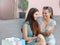 Two beautiful young women talking after shopping and sitting outdoors