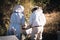 Two beekeepers using the bee smoker to calm and stun the bees by blowing smoke over the hive