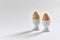 Two beige eggs in egg cups on a white