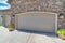 Two beige sectional garage doors with arched bricks door opening