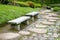 Two benches, green plants, flowers, stone road