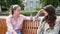 Two best friends talking outside, sitting on a bench in a park. Women friendship on sunny day in the city conversation and