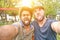 Two best multiracial friends taking selfie with mobile phone camera - Young multi ethnic people having fun making funny faces -