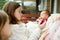 Two big sisters admiring their newborn brother. Two young girls holding their new baby boy. Kids with large age gap. Big age