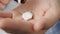 Two big white square pills fall into palm of hand from pill bottle. Close-up, front view, center composition