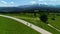 Two bikers cycling on the mountain empty road, aerial view. In the background wide mountain range and epic alpine view.