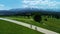 Two bikers cycling on the mountain empty road, aerial view. In the background wide mountain range and epic alpine view.