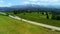 Two bikers cycling on the mountain empty road, aerial view. In the background wide mountain range and epic alpine view.