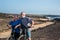 Two bikers with e bike stop to rest after a long excursion on the footpath along the atlantic ocean. Couple of senior people man