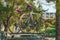 Two bikes are mounted on the roof curb on the roof of the car under the green trees in the shade. Bicycle transportation during