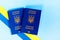 Two biometric passports of Ukrainian citizens on a blue background and with a yellow and blue ribbon.