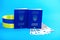 Two biometric passports of Ukrainian citizens and euro banknotes on a blue background with a yellow and blue ribbon.